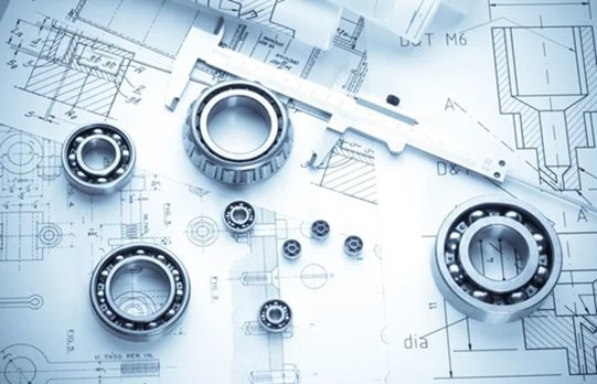 Engineering components, including ball bearings and a caliper, arranged on top of technical blueprints, illustrating the precision and complexity involved in custom machine building